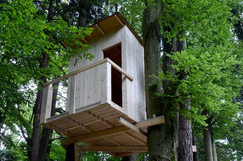 RHB Assets From IGX: Treehouse balcony with wooden railings overlooking a lush forest