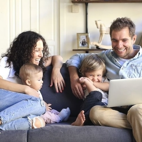 A distressed white house with boarded up windows.