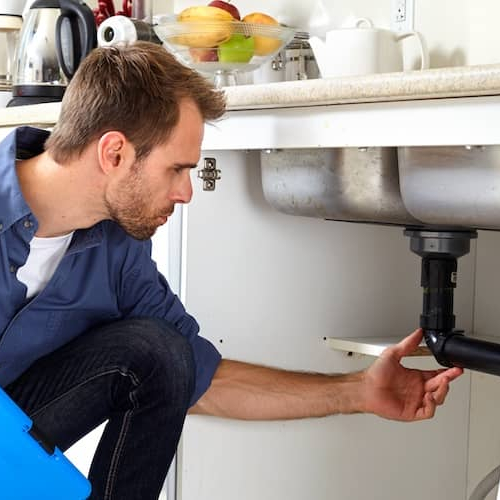 Plumber Inspecting Sink In House