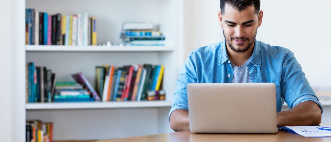 A man researching on a computer, likely conducting real estate or financial research online.