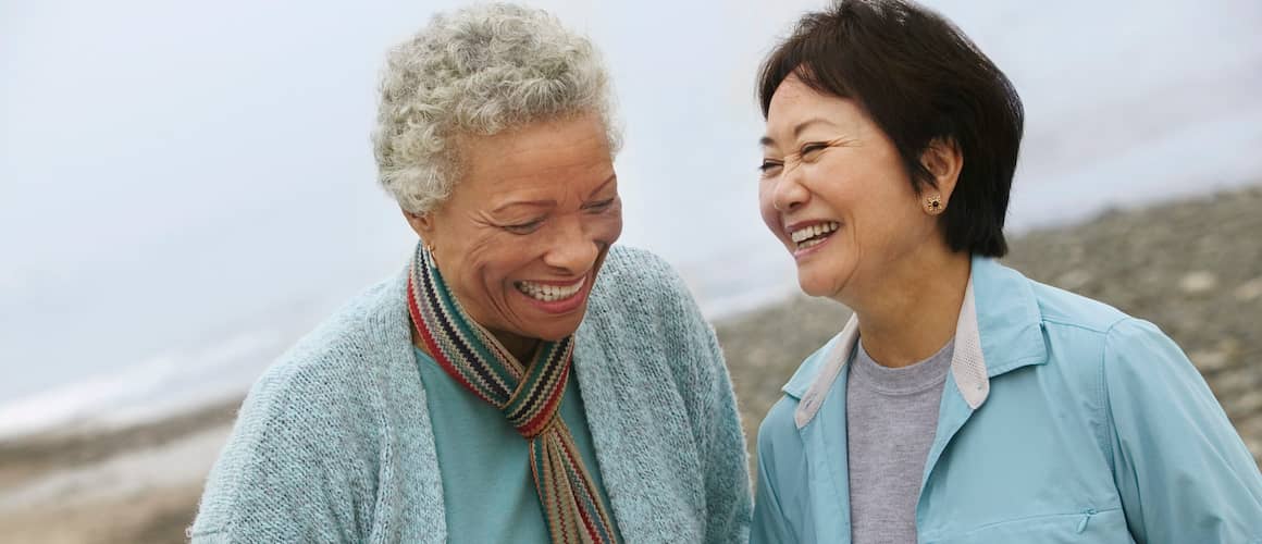 Older women laughing on the beach.