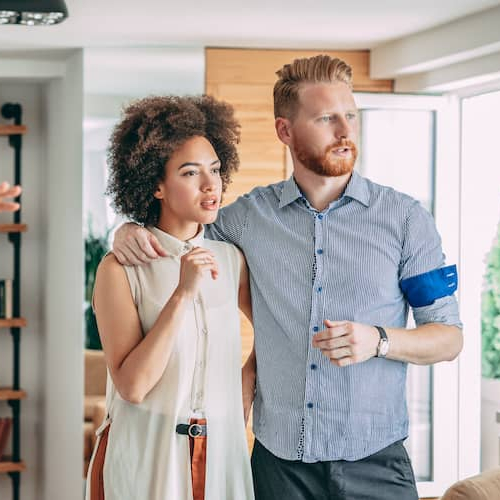 RHB Assets From IGX: Young couple looking at a house with real estate agent, alternative angle
