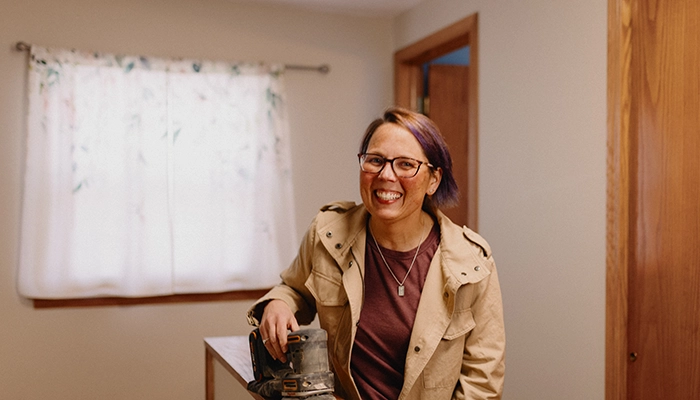 Woman laughing while sanding a banister.
