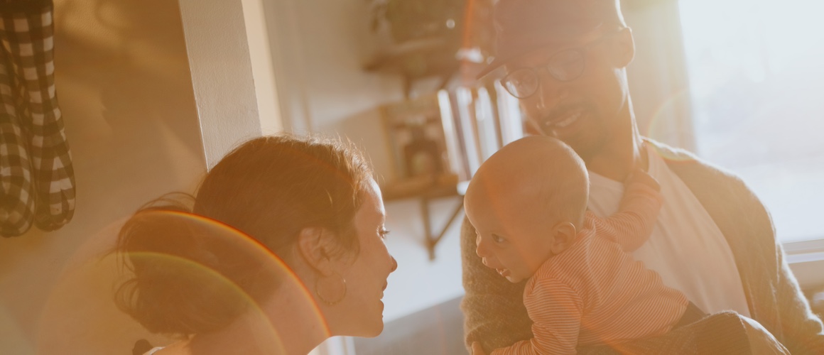 Mother looking at baby being held by father in their cozy home.