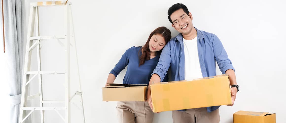 An Asian couple carrying boxes while moving into a new home.