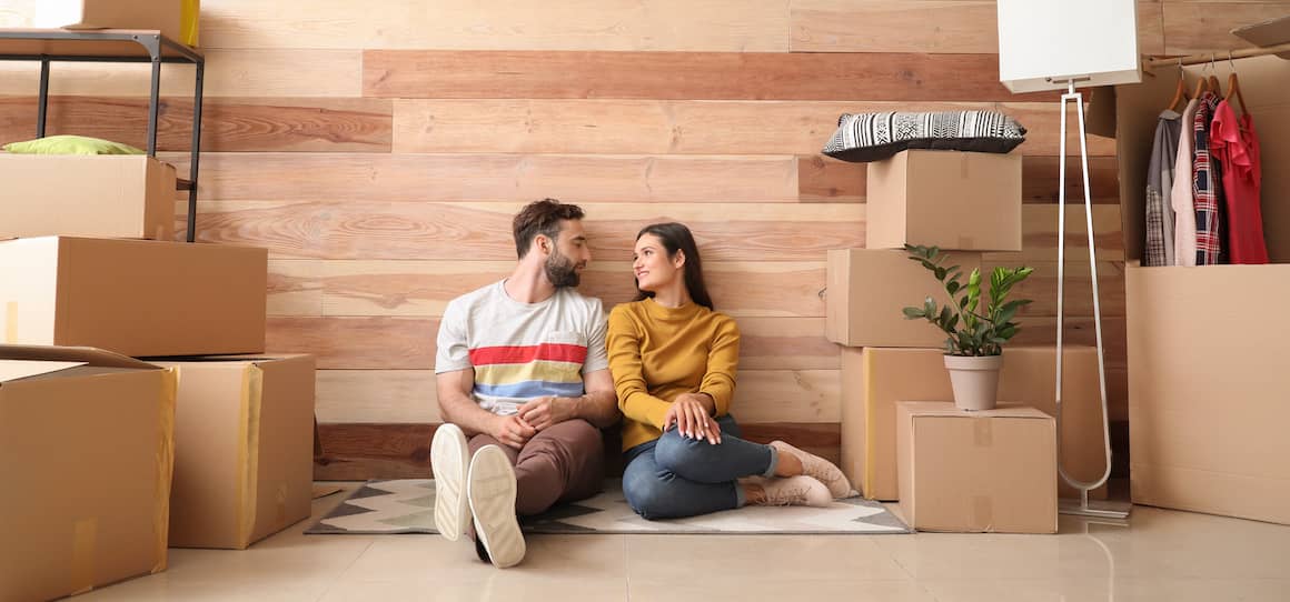 A couple inside a new house, engaged in the unpacking process.
