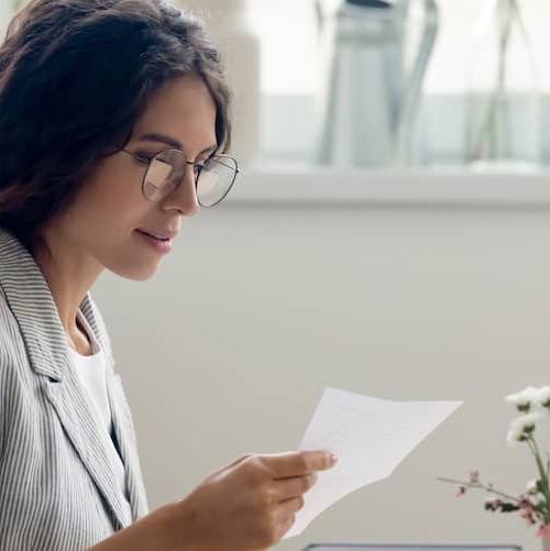 A woman looking at mail, potentially in a home or personal finance context.
