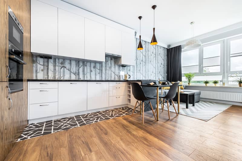 Open floor plan style kitchen with birch tree forest wallpaper backsplash.