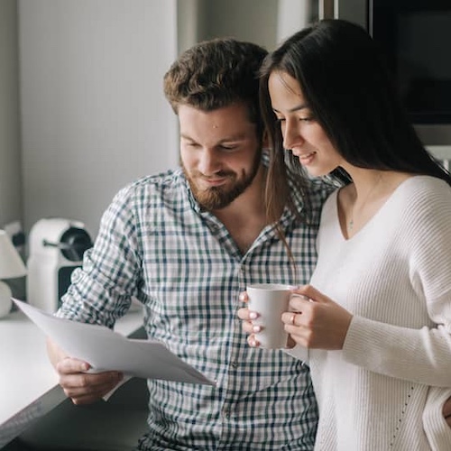 Young couple in the kitchen together looking at documents.