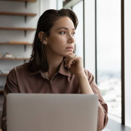 A woman looking out a window, possibly pondering or reflecting.
