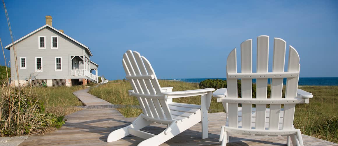 Two beach chairs on a boardwalk, depicting a serene beachside setting.