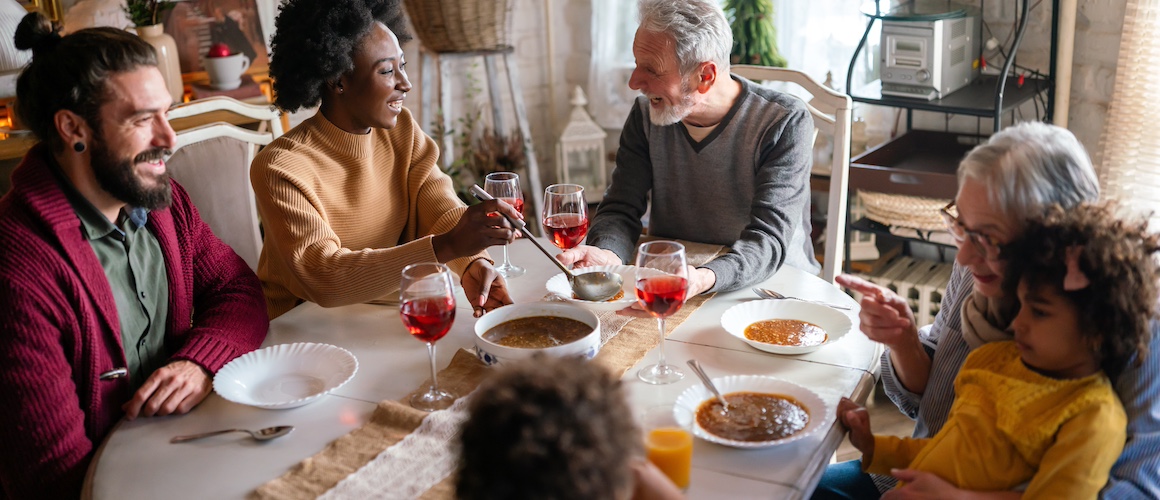 Multigenerational family enjoying family dinner at a large dinner table together.