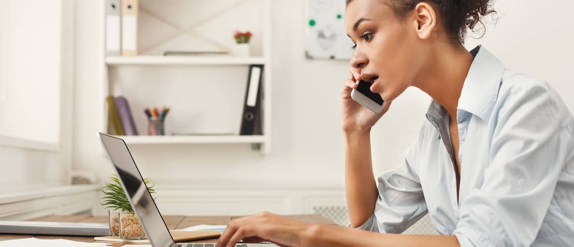 A woman multitasking on a phone call and a laptop maybe discussing a deal.