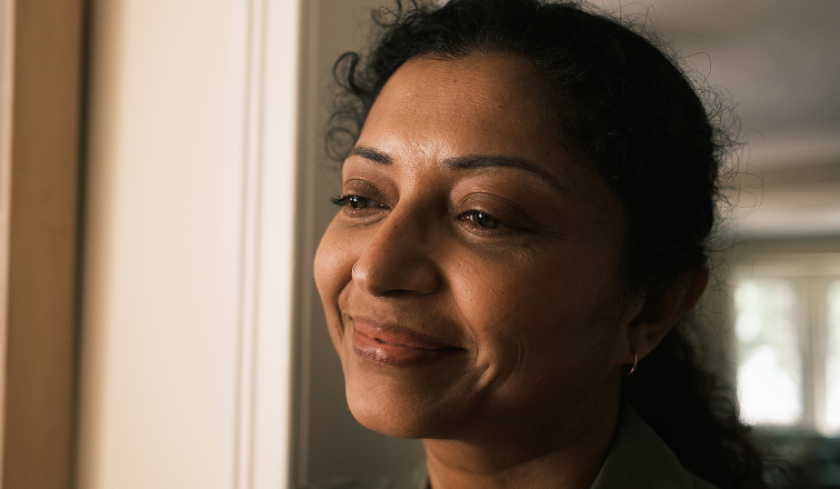 A woman smiles to herself while staring thoughtfully.
