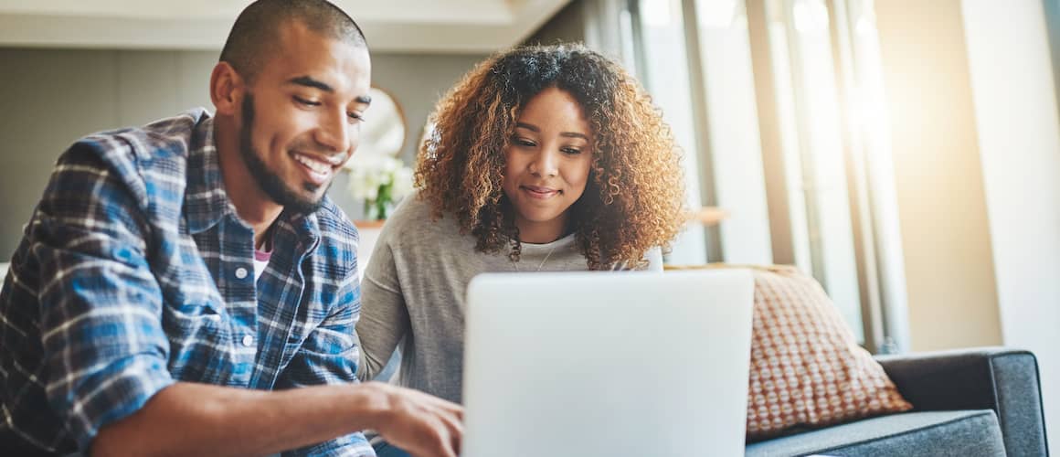 Young couple working on laptop computer and smiling.