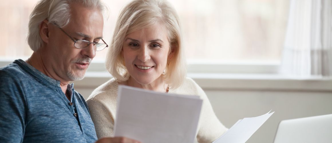 An elderly couple possibly looking at property or mortgage paper.