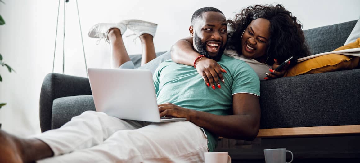 African American couple hanging out together at home on a couch.