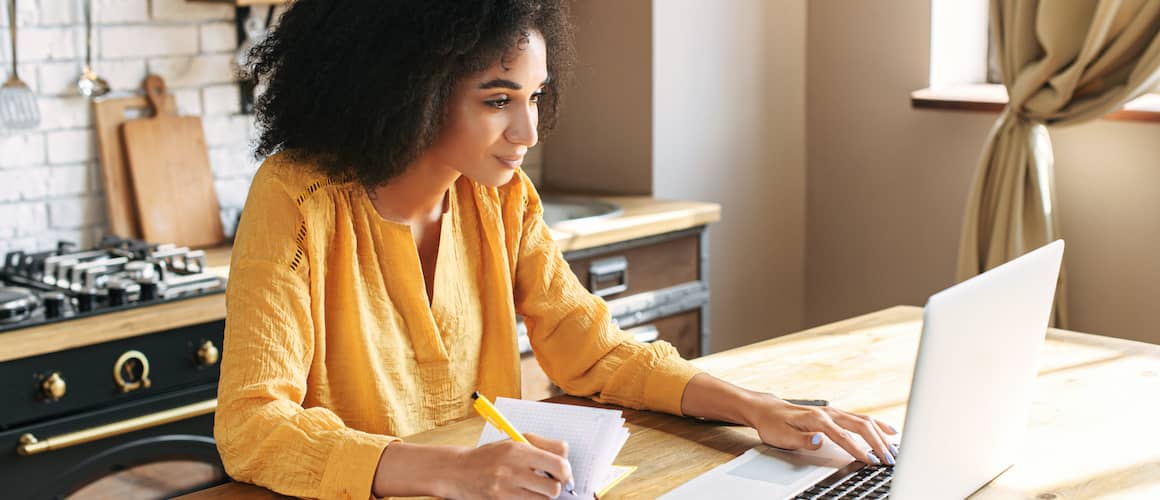 Woman in yellow shirt working on her laptop.