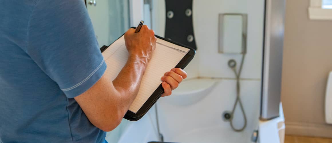Contractor writing inspection checklist while renovating a bathroom.