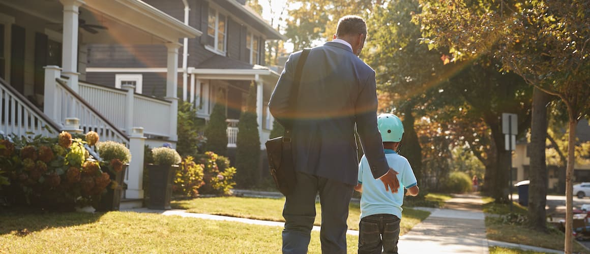 A dad walking with his son on a sidewalk.