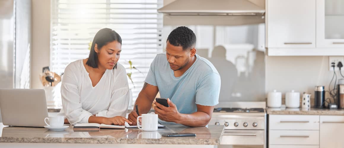 Couple discussing finances over coffee in their kitchen.