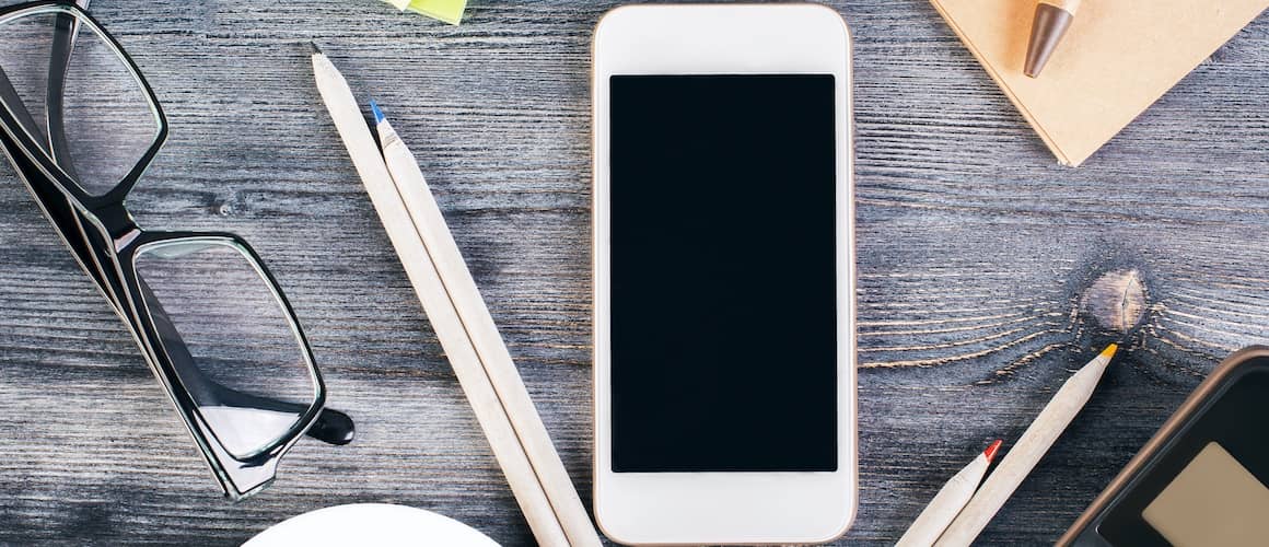 Mortgage calculator, pencils and phone on wooden table.