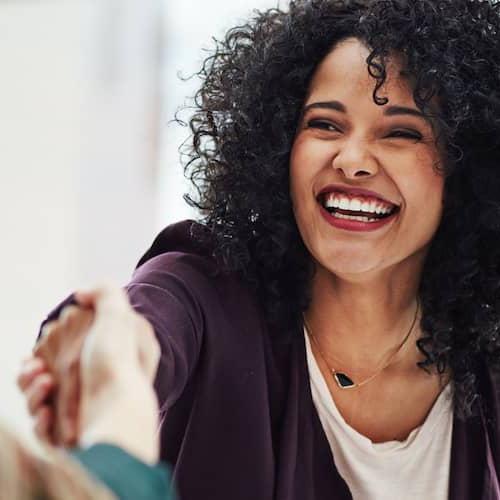 Two businesswomen shaking hands, representing a successful business agreement or partnership.