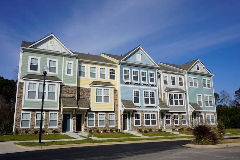 Exterior view of a row of multicolored three story townhomes.