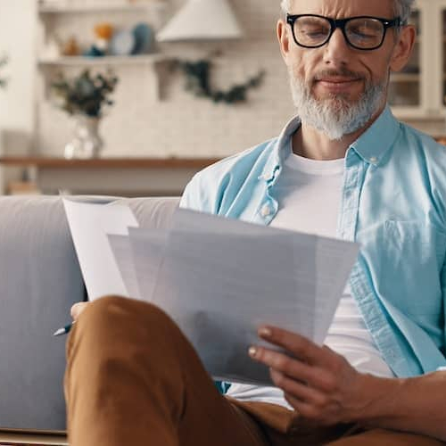 Middle-aged man applying for a loan while sitting on couch.