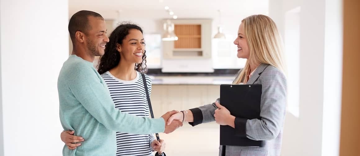 Couple shaking hands with an agent, possibly after finalizing a real estate deal or signing an agreement.