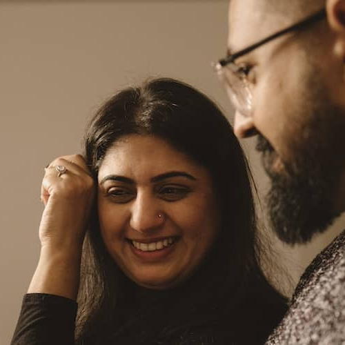 Couple sitting on couch and smiling at one another.