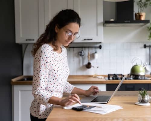 A woman reviewing her finances from her kitchen island.