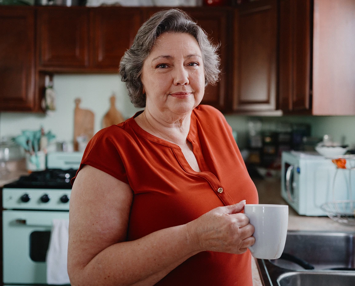 Older woman standing in a kitchen by a countertop