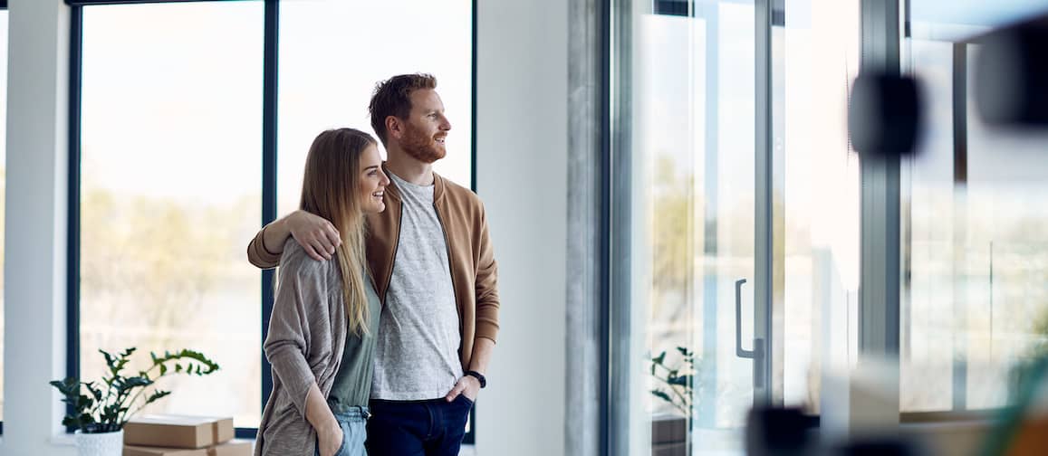 A couple looking out of a window, symbolizing contemplation or envisioning their future home.