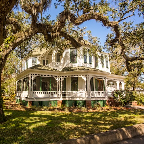 Large house in Georgia with an old tree in the forefront. 