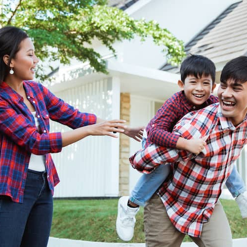 An Asian family enjoying family moments outside a white house.