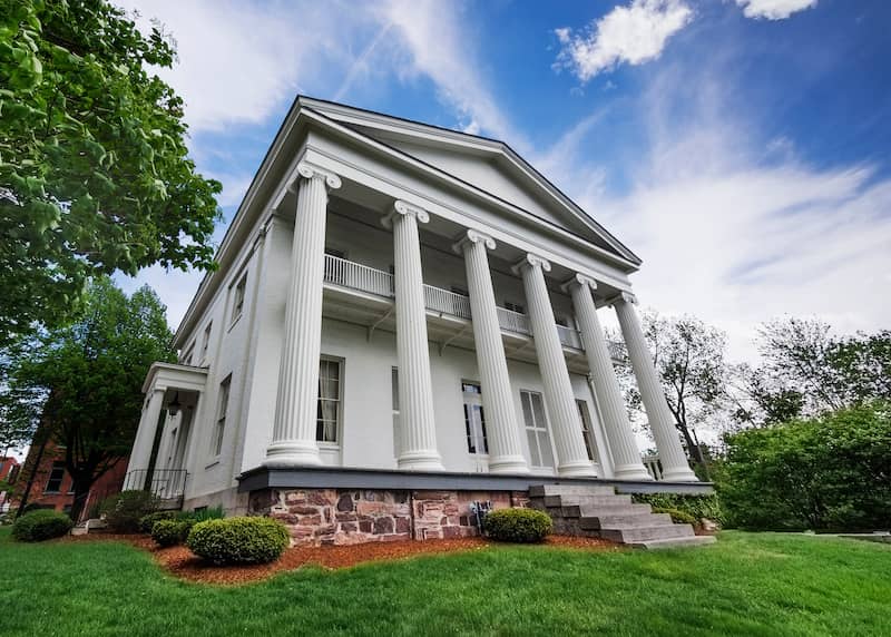 Exterior view of a white Greek revival home with grand columns.