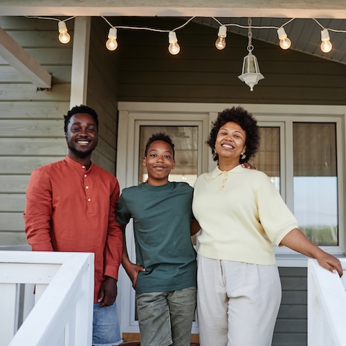Middle-aged couple with teen son on front porch of new home.