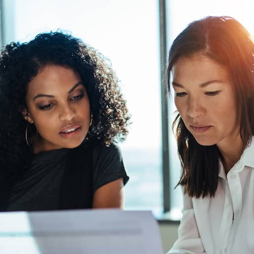 Two women looking over mortgage documents together at signing.