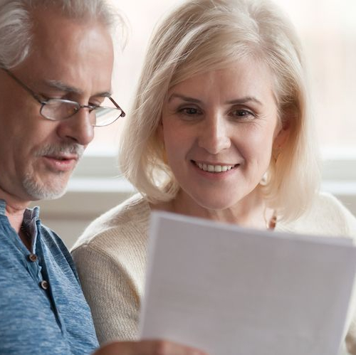 An elderly couple possibly looking at property or mortgage paper.