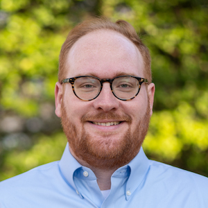 Headshot of a red-headed man smiling straight at the camera.