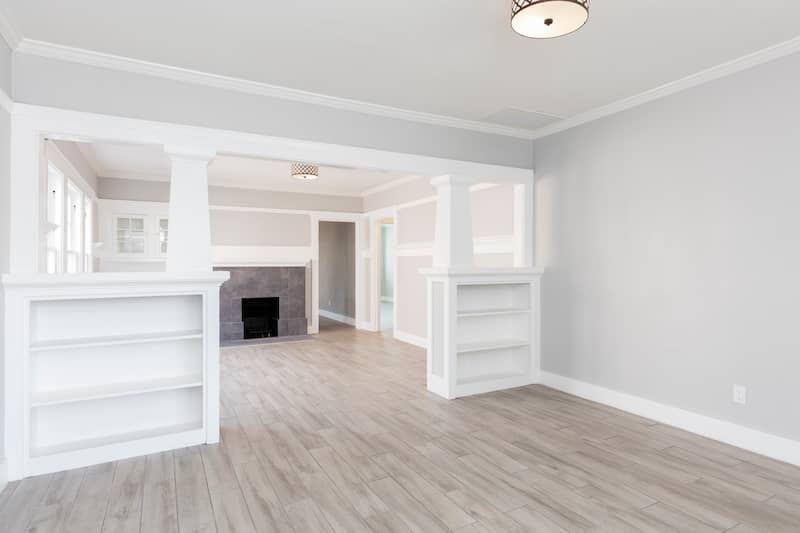 Interior of a small home with wooden floor and a fireplace.