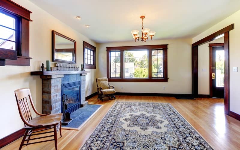 Brick fireplace in a spacious living room with light wood floors and dark trim. 