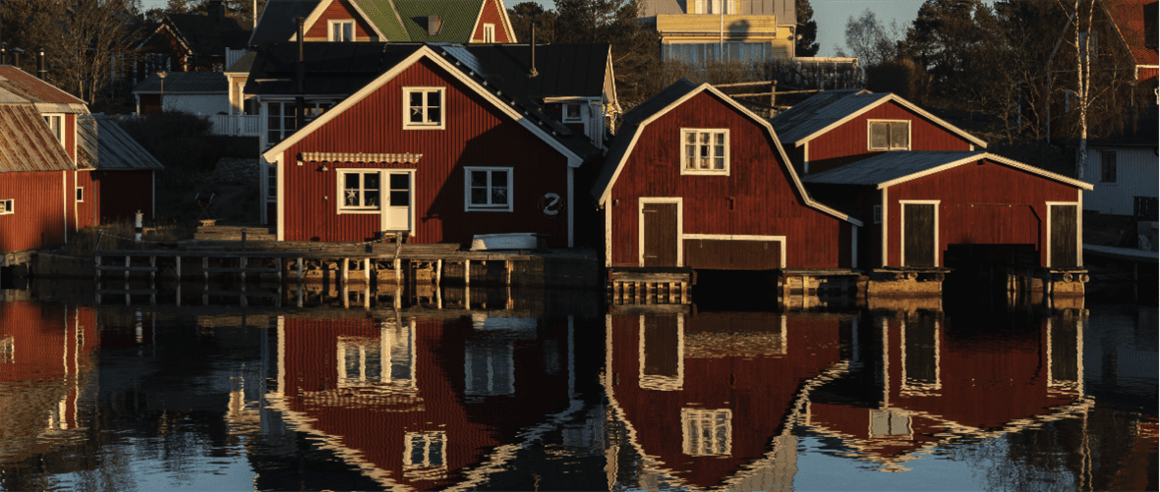 Red houses by a lake, depicting houses in a scenic setting.