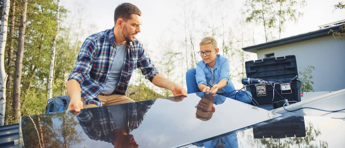 Father and son installing solar panels on their home.