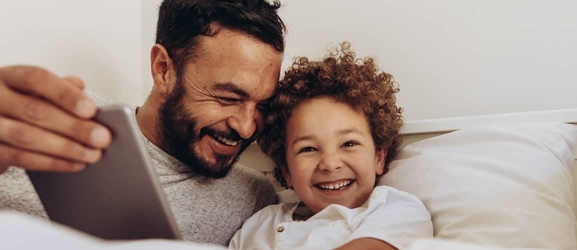 A father and son having a moment and watching something on the tablet.