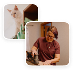 Person sanding a wooden surface indoors with a cat nearby
