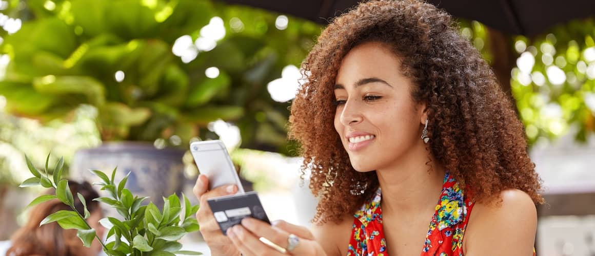 Woman typing credit card number on phone.