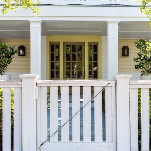 A white fence in front of a residential property.