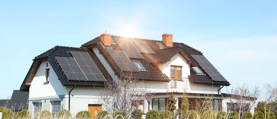 White two story home with black roof and solar panels.